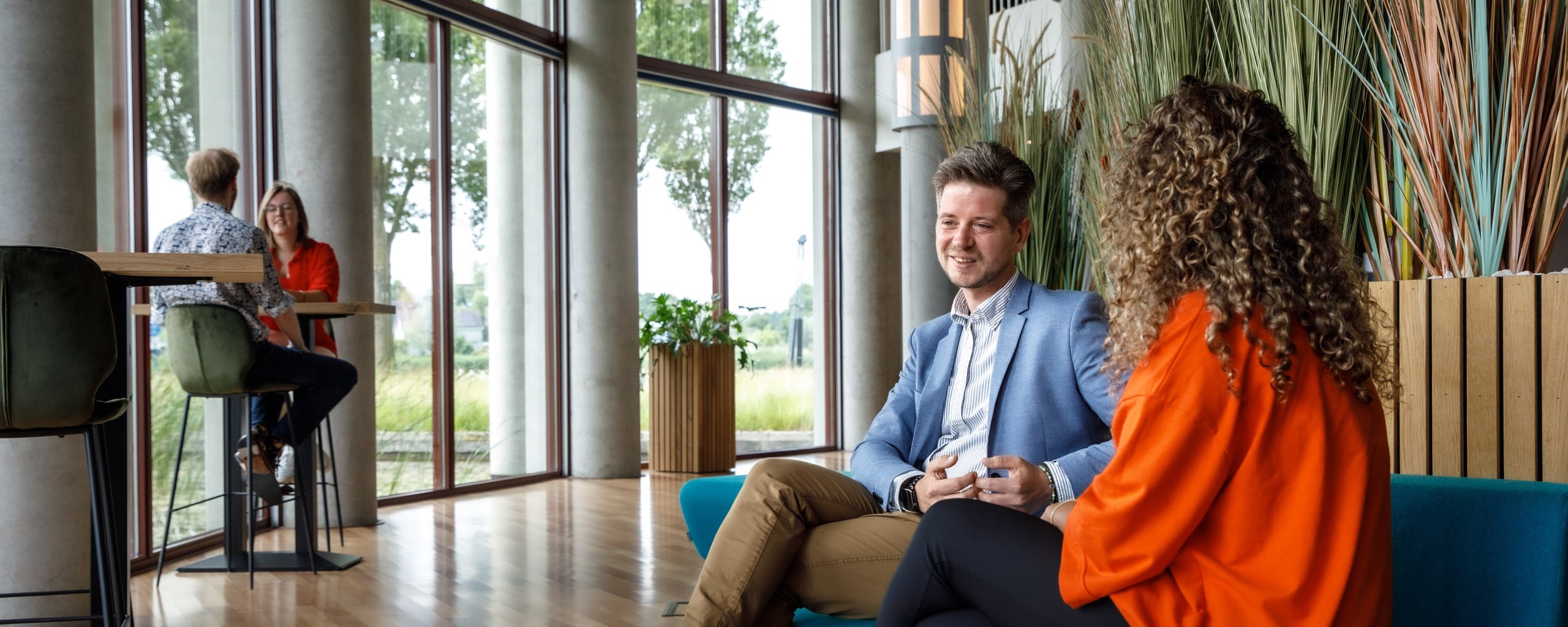 Medewerkers zittend op een bankje in het atrium van het hoofdgebouw Noorderzijlvest